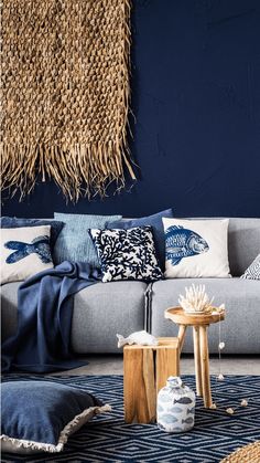 a living room with blue walls and pillows on the couch, coffee table and side tables