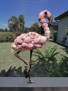 a flamingo made out of seashells on a stand