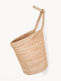 an empty basket hanging on the wall with a wooden stick sticking out of it's side