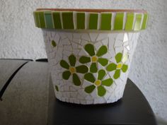 a green and white flower pot sitting on top of a black table next to a wall