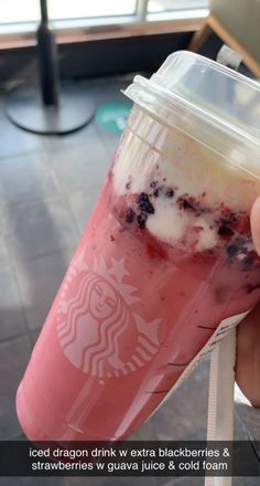 someone holding up a starbucks drink with ice and berries on it in front of a window