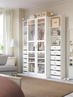 a living room filled with furniture and lots of white storage space next to a window