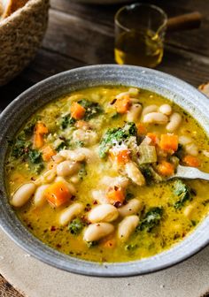 a white bowl filled with soup next to bread on top of a wooden table,