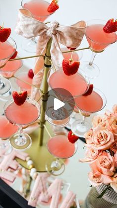 a table topped with lots of glasses filled with pink liquid and covered in strawberries