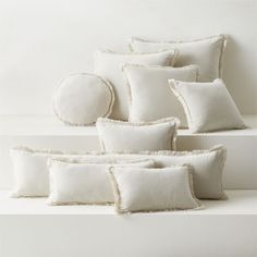 six white pillows stacked on top of each other in front of a white wall and floor