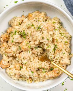 a white bowl filled with rice and meat covered in parsley on top of a table