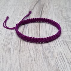 a close up of a purple bracelet on a wooden table with white wood planks