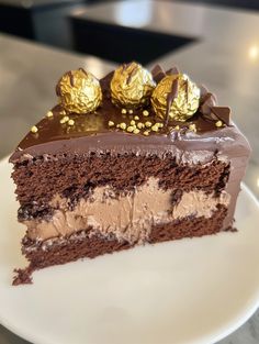 a piece of chocolate cake on a white plate with gold foiled candies around it