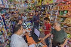 people in a grocery store looking at items on the shelves and using laptops to buy food