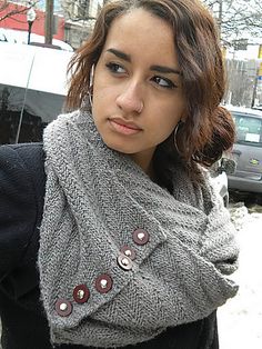 a woman wearing a gray scarf with buttons on the front and side, standing in snow