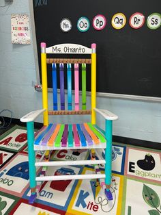 a child's wooden rocking chair in front of a chalkboard with writing on it