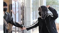 two people wearing face masks are holding hands