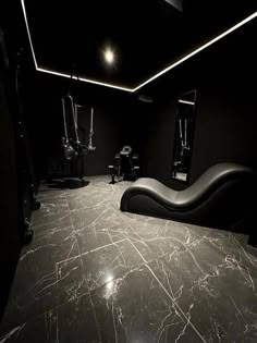 a room with black walls and marble flooring is lit by recessed lights, along with a curved bench in the center