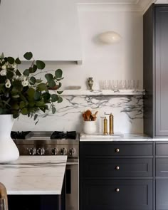 a kitchen with marble counter tops and black cabinets, white vases on the stove