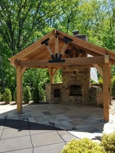 a gazebo built to look like an outdoor living area with fireplace and grill in it