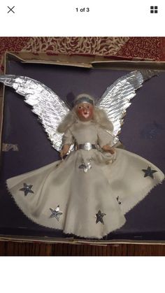 a white angel doll in a box with silver stars on it's body and wings