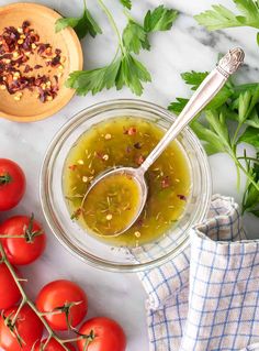 a bowl of olive dressing next to tomatoes and parsley