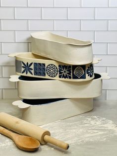 stack of ceramic bowls and wooden spoons on counter top next to white brick wall