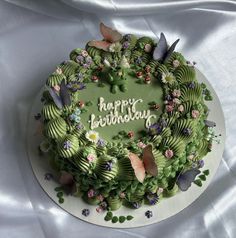 a green birthday cake decorated with flowers and butterflies