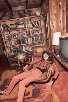 a woman laying on the floor in front of a tv and bookshelf full of books