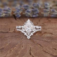 an engagement ring on top of a piece of wood with lavenders in the background