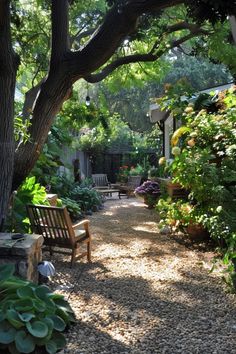 Cozy backyard seating area under a shaded garden with pebble pathways and lush greenery. Ideal for DIY backyard patio and garden landscaping. Backyard Landscaping Natural, The Art Of Outdoor Living, Stone Backyard Landscaping, Romantic Backyard Landscaping, Easy Maintenance Backyard, Council Garden Ideas, Gravel Path Backyard, Lawnless Backyard, Craftsman Style Backyard