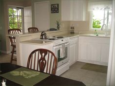 a kitchen with an oven, sink and dining room table in front of the window