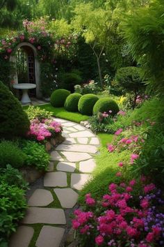 a garden with lots of flowers and plants on the side of it, along with a stone path