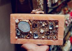 a person holding up a small box with some stones and crystals on it in their hand