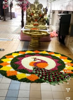 a large flower arrangement on the floor in front of a buddha statue and other decorations