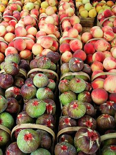 many different types of fruit in baskets on display for sale at a grocery store, including peaches and figs