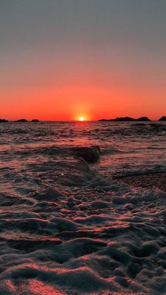 the sun is setting over the ocean with waves