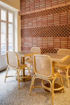 a dining room table and chairs in front of a wall made out of brick tiles