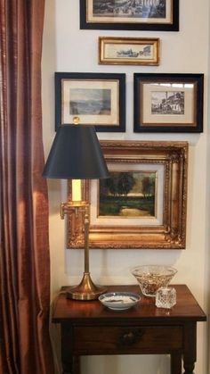 a table with a lamp and pictures on the wall