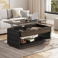 a living room with a couch, coffee table and laptop on top of it in front of a window