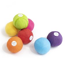 five balls of colored wool are arranged in a row on a white surface with labels