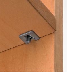 the corner of a wooden cabinet with a metal latch on it's door handle