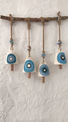 three small blue and white objects hanging from a rope on a wall next to a wooden stick