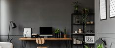 a desk with a computer on top of it next to a chair and bookshelf