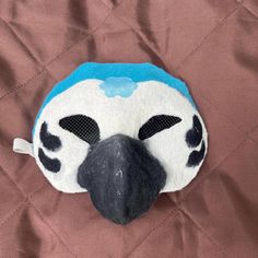 a blue and white bird with black eyes on a brown background, it's head is made out of fabric