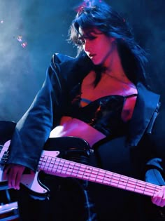 a woman holding a bass guitar on stage