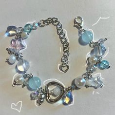 a silver bracelet with blue and white glass beads, heart charms and hearts on it