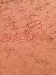 i love baseball written in the sand with a bat next to it and an inscription on the ground