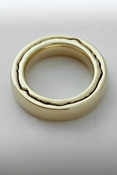 a gold wedding ring on a white surface