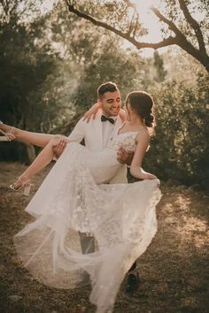 a bride and groom are dancing in the woods