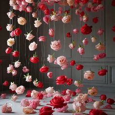 an arrangement of pink and red flowers hanging from strings