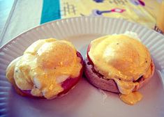 two eggs benedicts sitting on top of a paper plate