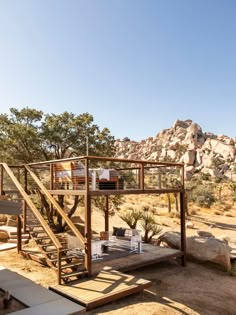 a wooden structure sitting in the middle of a dirt field next to rocks and trees