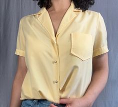 Vintage yellow polo blouse in great condition. There's a button missing on the bottom, but everything looks great otherwise. Measurements:  Shoulder: 16 inches Bust(armpit to armpit): 20 inches Sleeve: 8 inches Cuff: 6.5 inches Length: 26 inches PLEASE READ MEASUREMENTS *All items are measured flat. Measurements are not doubled.* EXCHANGE/STORE CREDIT ONLY Please view return policy DISCLOSURE Some items have been professionally cleaned and altered. Photos and measurements reflect the current sta Luxury Yellow Short Sleeve Blouse, Yellow Summer Blouse With Pockets, Yellow Blouse With Pockets For Summer, Spring Yellow Tops With Pockets, Yellow Workwear Tops With Pockets, Spring Yellow Shirt With Pockets, Yellow Work Shirt With Pockets, Yellow Collared Shirt For Work, Collared Yellow Shirt For Work