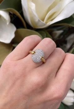 a woman's hand with a diamond ring on it and flowers in the background